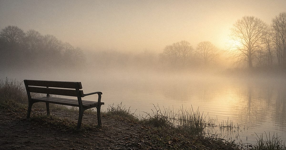 A wooden bench by a misty lake at sunrise